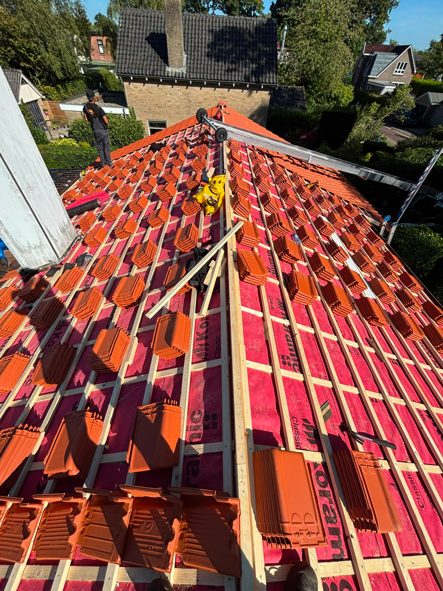 Dakpannen worden gelegd op nieuwe panlatten tijdens een dakrenovatie